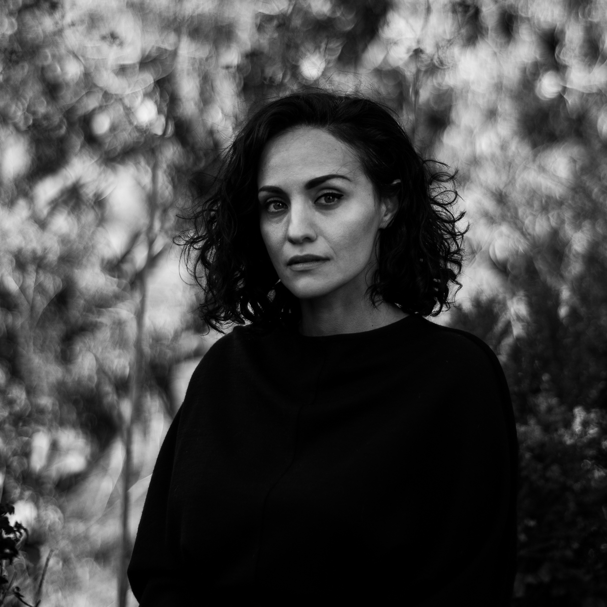 Sholeh Asgary looks out calmly against a blurred background of nature and trees