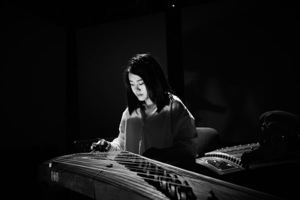 Yu Miao, plays the guzheng in a dark room