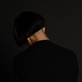 A mostly black photo of the back of a bowl-cut, sitting on top of a freshly shaved head (cut by Tom, a now-retired barber somewhere in Pittsburgh